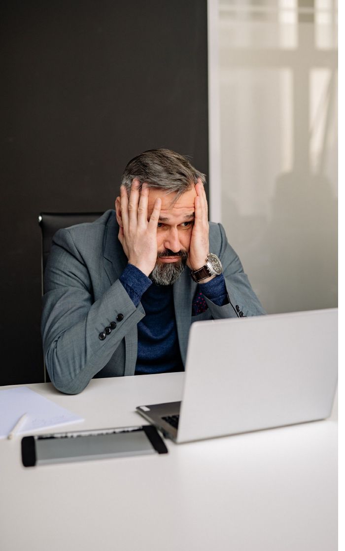Older worker stressed at desk, being pushed out of a job